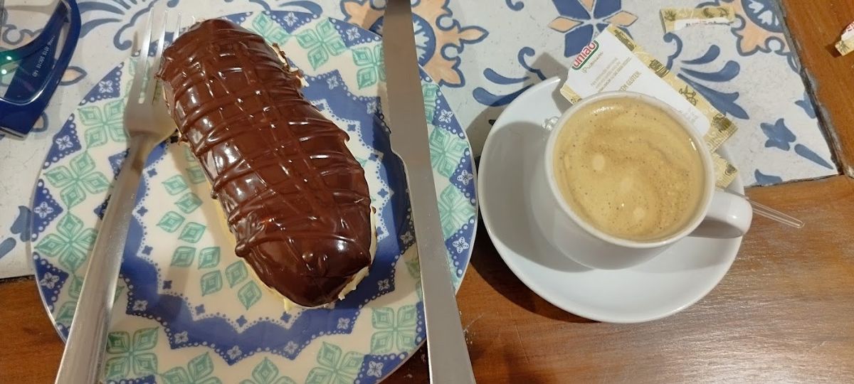 Bomba de chocolate ao lado de um café com leite