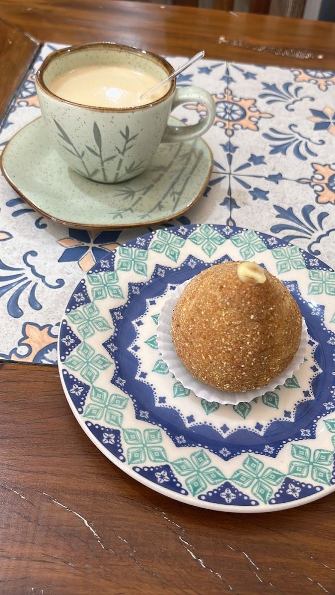Coxinha num prato de ladrilho azul ao lado de um café com leite