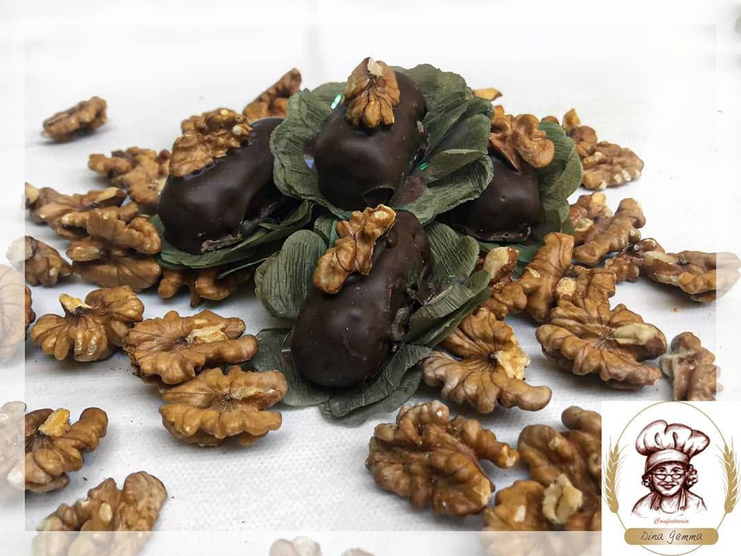Doces de nozes cobertos de chocolate sobre folhas e nozes
