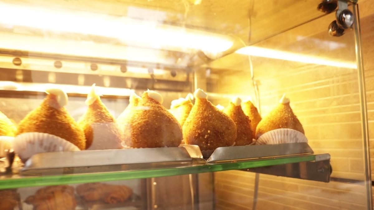 Vitrine iluminada cheia de coxinhas douradas